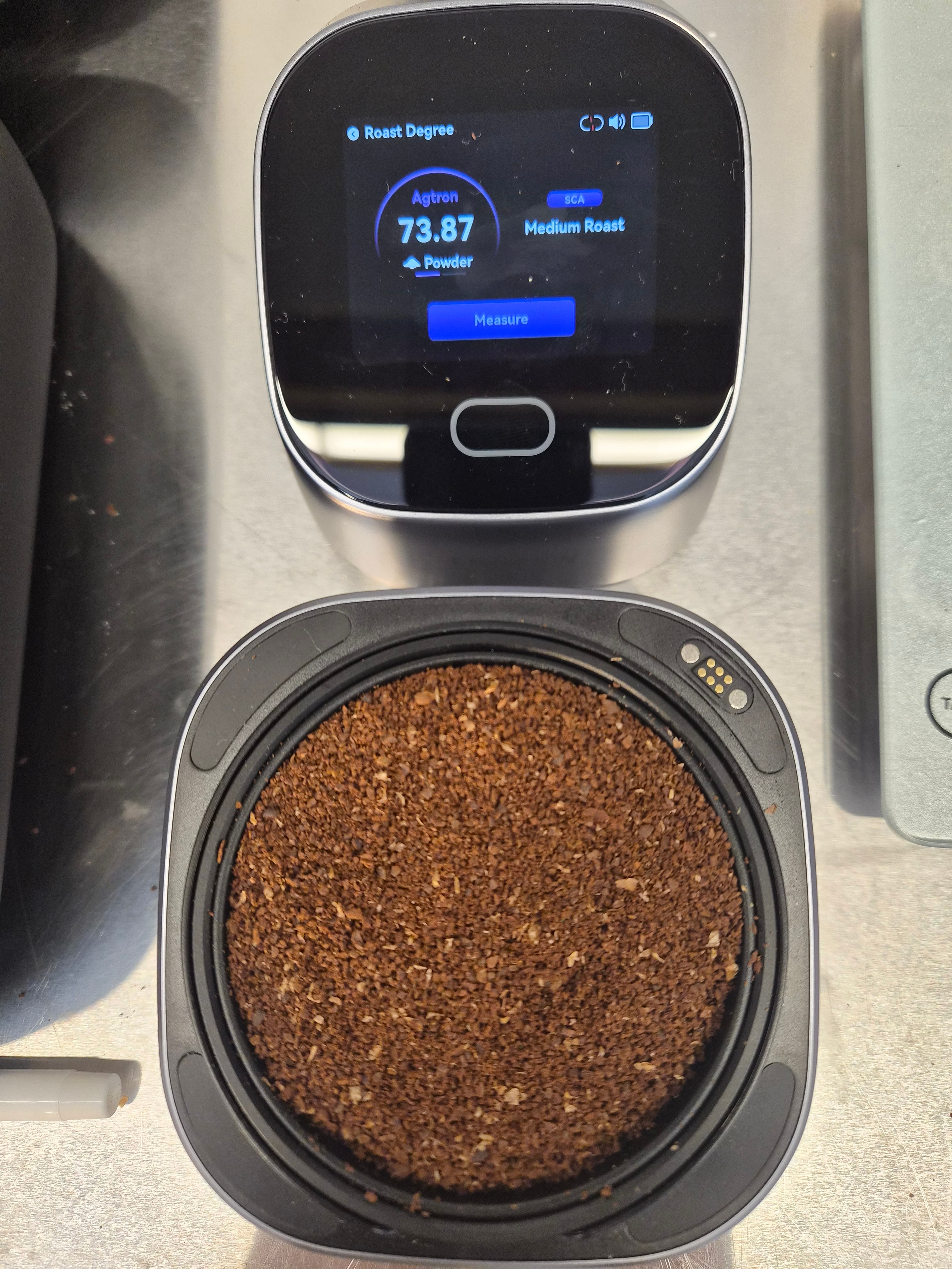 Agtron colorimeter reading 73.87 medium roast beside ground coffee sample